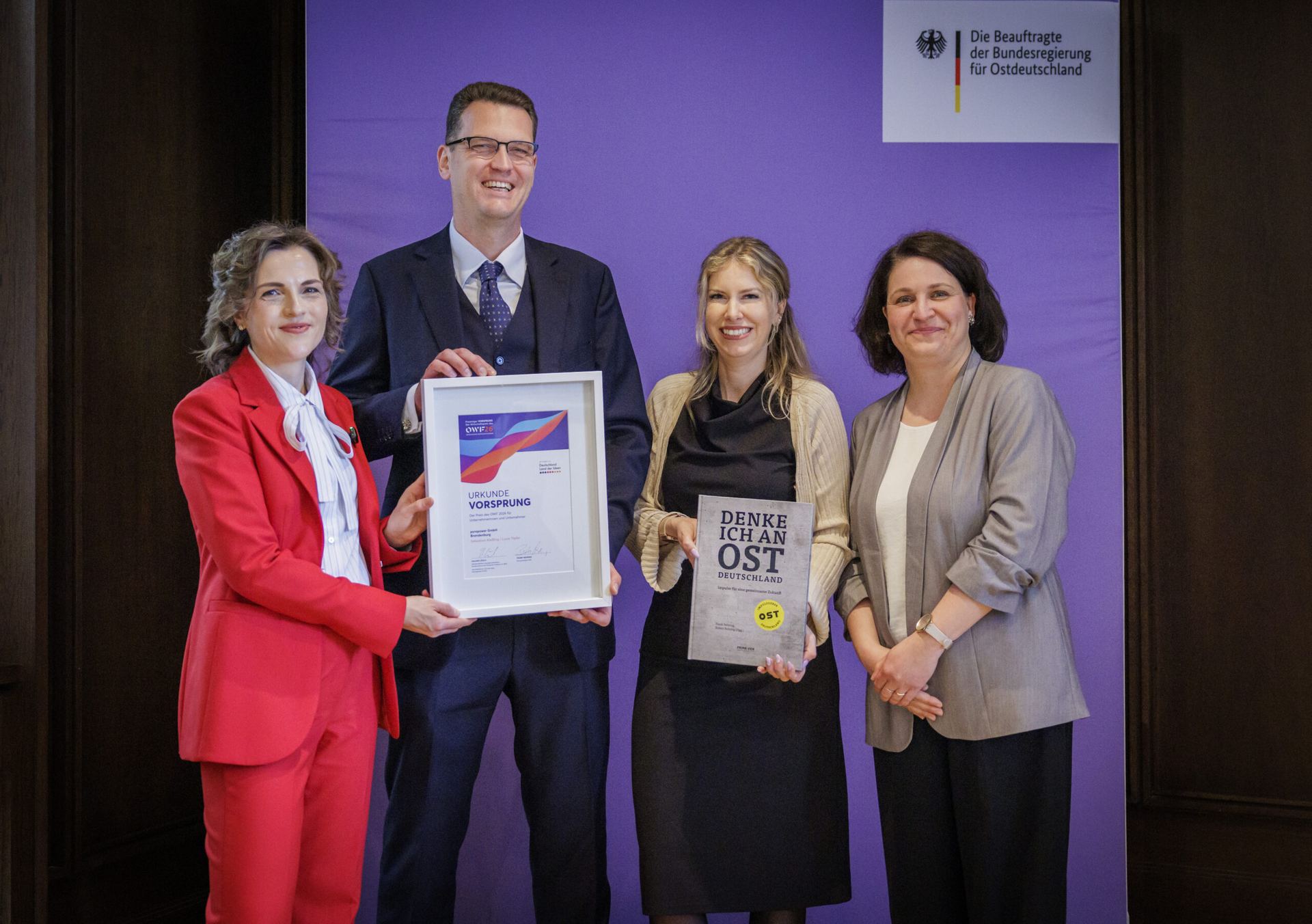 Preisverleihung im Bundesministerium der Finanzen: vier Personen mit Urkunde und Trophäe