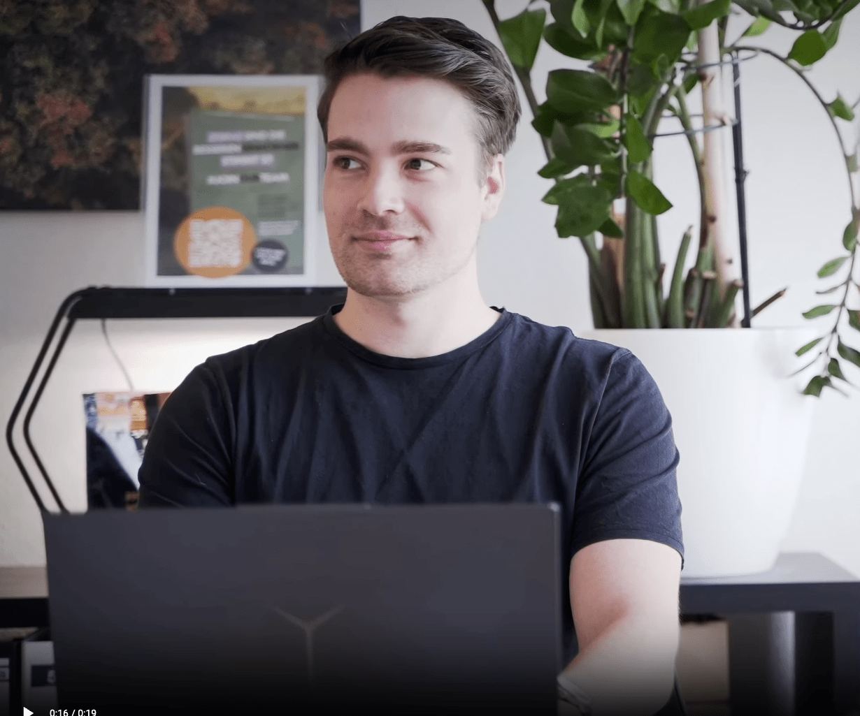 Mitarbeiter sitzt lächelnd am Laptop im Büro