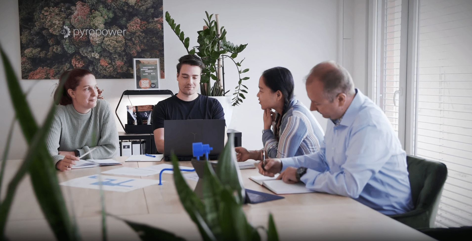 Vier Teammitglieder besprechen sich am Tisch vor einem Laptop