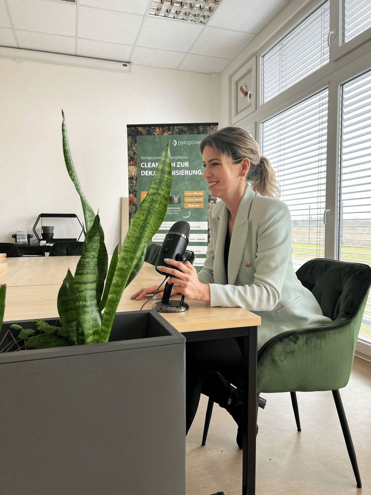 Frau sitzt am Schreibtisch im Büro und blickt auf ihr Smartphone