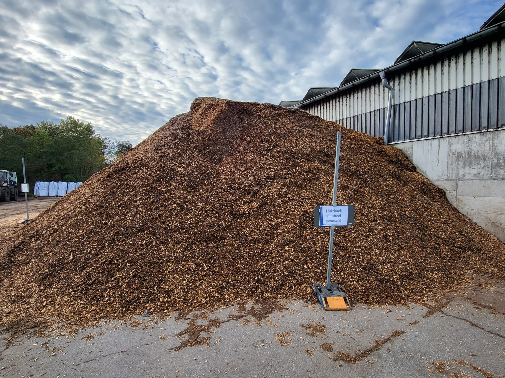 Großer Haufen Holzhackschnitzel vor einer Lagerhalle