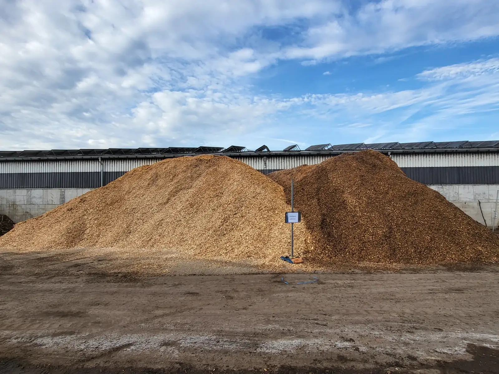 Haufen aus Holzhackschnitzeln vor einer Lagerhalle